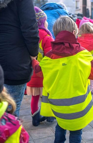 Immagine di bambini di schiena con il gilet che in gruppo compongono il piedubus