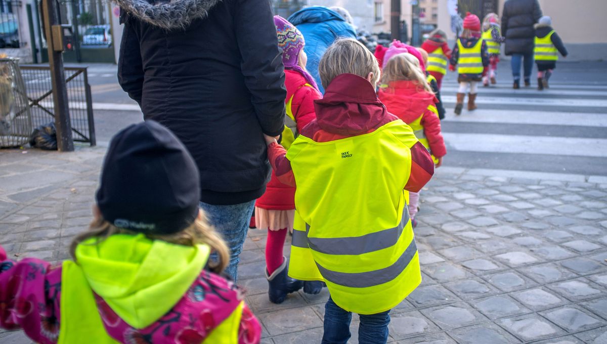 Immagine di bambini di schiena con il gilet che in gruppo compongono il piedubus