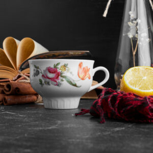 Immagine di una tazzina da tè con accanto un libro e altri elementi di decoro