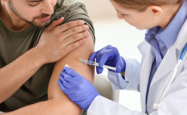 Doctor vaccinating young man in clinic