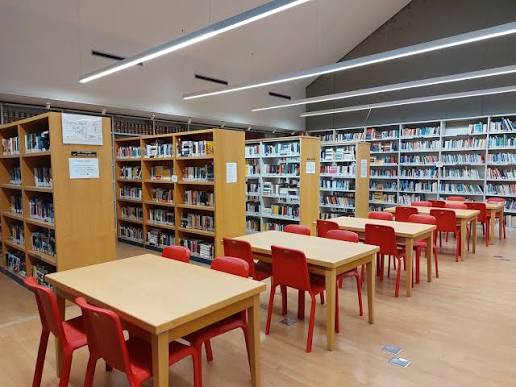 l'interno della biblioteca con scaffali tavoli e sedie
