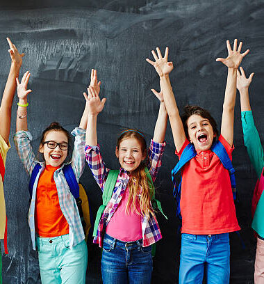 Excited schoolchildren standing with hands up