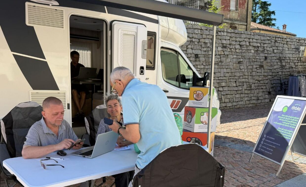 Foto generica del nuovo camper attrezzato con due operatori impegnati a dare informazioni a un cittadino anziano